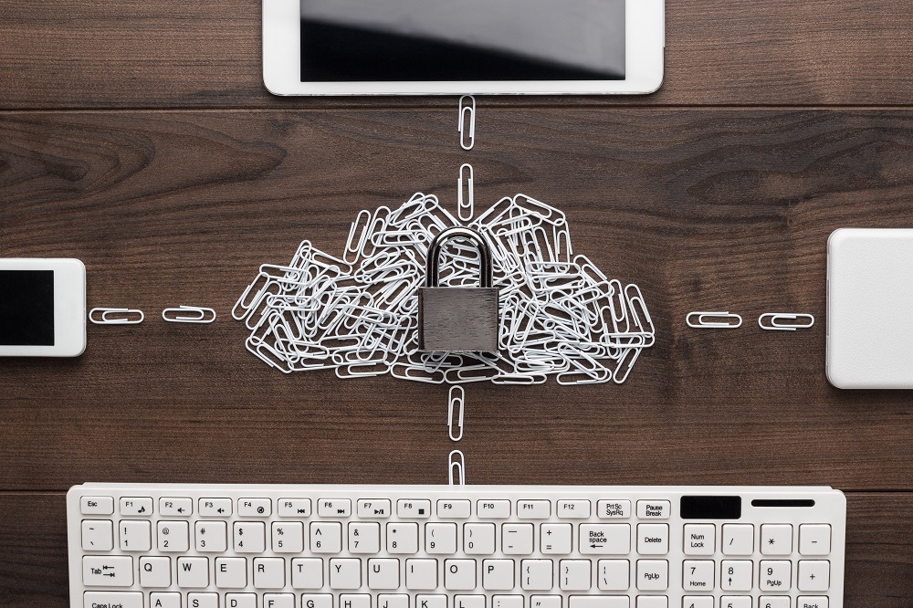 conceito de sistema em nuvem, com teclado e celulares em cima de uma mesa, conectados por clipes de papel que formam uma nuvem
