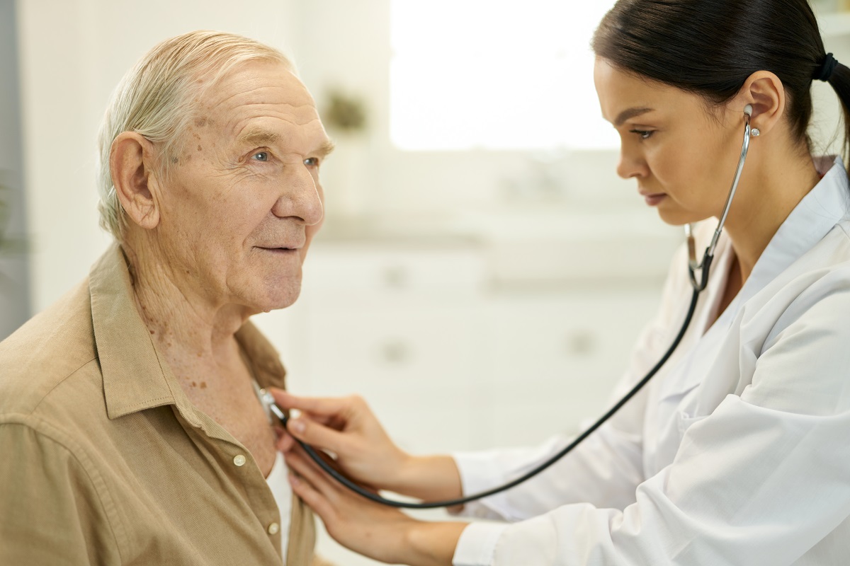 médica ouvindo batimentos cardíacos de paciente idoso com estetoscópio